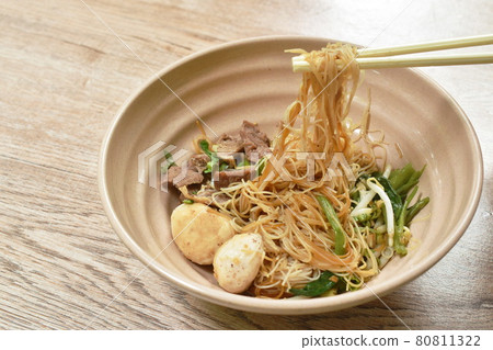boiled dry vermicelli thin rice noodles topping slice braised pork and meatball dressing sweet black soybean sauce picking by chopsticks on bowl boiled dry vermicelli thin rice noodles topping slice braised pork and meatball dressing sweet black soybean sauce picking by chopsticks on bowl 80811322