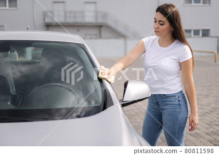 Attractive happy joyful female driver wipe her car using rag in self-service car wash 80811598