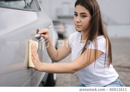 Front view of attractive happy joyful female driver washing her car with special rag in self-service car wash Front view of attractive happy joyful female driver washing her car with special rag in self-service car wash 80811611
