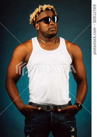 This is a studio portrait of an African American in sunglasses and a white T-shirt on a dark blue 80812569