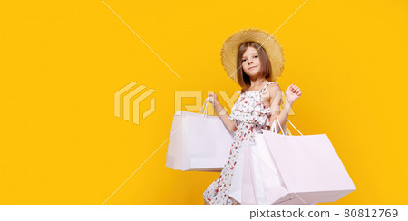 Portrait Of Joyful Teen Girl In Straw Hat With Bright Shopping Bags Over Yellow Background Portrait Of Joyful Teen Girl In Straw Hat With Bright Shopping Bags Over Yellow Background 80812769