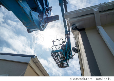 Worker on a aerial access platform, cherry picker, cleaning house 80814510