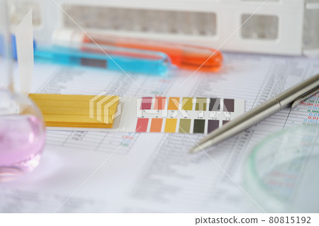 Test tubes with blue and orange liquid with test results on table 80815192