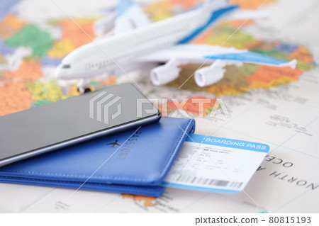 Smartphone with passport and tickets and an airplane lie on geographic map closeup 80815193