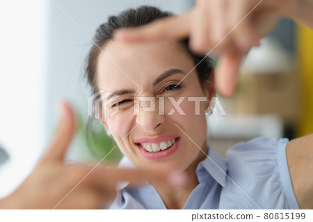 Young woman winks and makes a gesture with hands to photo frame Young woman winks and makes a gesture with hands to photo frame 80815199