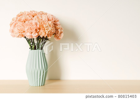 Beige carnation in light green ceramic vase on light wooden table. Beige carnation in light green ceramic vase on light wooden table. 80815403