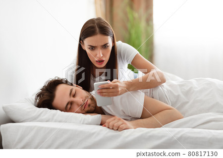 Wife Reading Message On Phone While Cheating Husband Sleeping Indoor 80817130