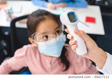 Teacher with contactless thermometer measuring temperature of asian pupil Teacher with contactless thermometer measuring temperature of asian pupil 80817212