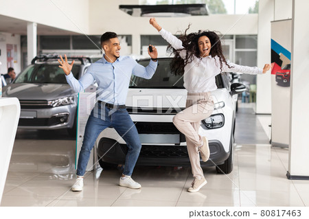 Emotional young couple dancing in car saloon, holding key 80817463