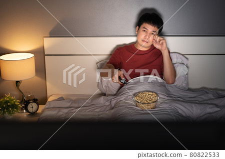 sad man watching television and crying on a bed at night (romantic movie) 80822533