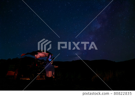 A woman sits in a farmer's automobile, gazing at the stars in the night sky, with the Milky Way in the background. A woman sits in a farmer's automobile, gazing at the stars in the night sky, with the Milky Way in the background. 80822835
