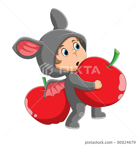 The boy with the bat costume is holding the apple 80824679