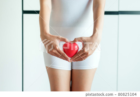 Woman hands holding red heart model on crotch with leucorrhoea 80825104