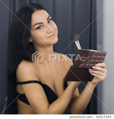 Brunette wearing only a bra sitting by the mirrow 80825426