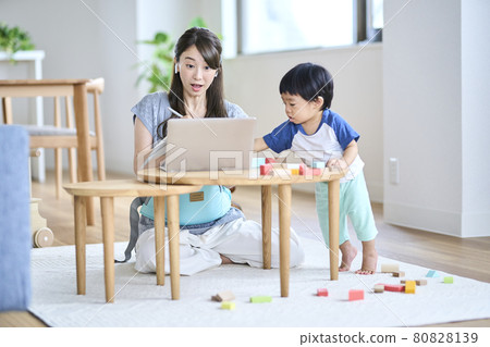 A woman having an online meeting in the living room with children A woman having an online meeting in the living room with children 80828139