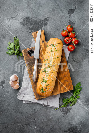 Sliced grilled bread with garlic and herbs, on gray stone table background, top view flat lay, with copy space for text Sliced grilled bread with garlic and herbs, on gray stone table background, top view flat lay, with copy space for text 80828327