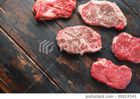 Set of organic raw beef steakes rump, chuck roll and top blade cut on old rustic dark wooden background, top view with space for text. Set of organic raw beef steakes rump, chuck roll and top blade cut on old rustic dark wooden background, top view with space for text. 80828341