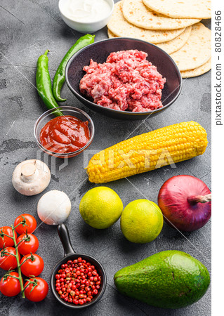 Ingredients for beef meat mexican tacos , corn tortillas, chili pepper, avocado, meat on textured grey background, side view. Ingredients for beef meat mexican tacos , corn tortillas, chili pepper, avocado, meat on textured grey background, side view. 80828466