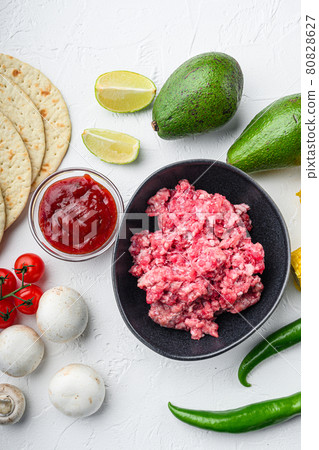 Minced beef meat with raw ingredients for tacos with , corn tortillas, chili, avocado, over white background. Top view. Minced beef meat with raw ingredients for tacos with , corn tortillas, chili, avocado, over white background. Top view. 80828627
