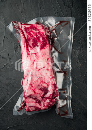 Raw rib eye beef meat steak cut in vacuum packaging, on black stone background, top view flat lay Raw rib eye beef meat steak cut in vacuum packaging, on black stone background, top view flat lay 80828656