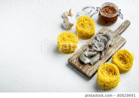 Pasta with shrimp, tomato and pesto sauce ingredients, on white stone surface, with copy space for text Pasta with shrimp, tomato and pesto sauce ingredients, on white stone surface, with copy space for text 80828691