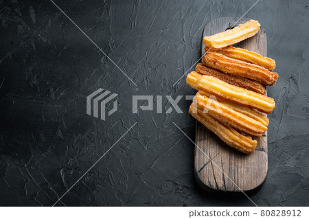 Tasty churros with chocolate caramel sauce, on black background with space for text, copyspace Tasty churros with chocolate caramel sauce, on black background with space for text, copyspace 80828912