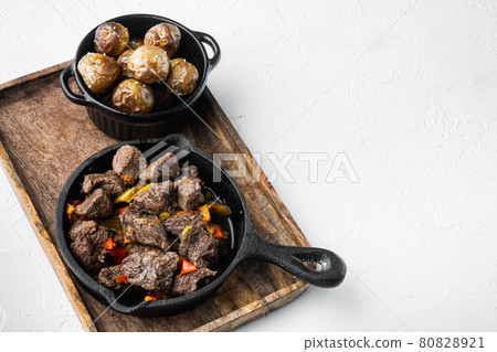 Meat stew with sweet bell pepper and bay leaf, in cast iron frying pan, on white stone surface, with copy space for text Meat stew with sweet bell pepper and bay leaf, in cast iron frying pan, on white stone surface, with copy space for text 80828921