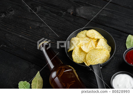 Home made potato chips, and bottle of beer , on black wooden background, with copy space for text Home made potato chips, and bottle of beer , on black wooden background, with copy space for text 80828993