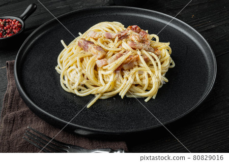 Carbonara pasta dish. Traditional Roman cuisine. Italian food, on black wooden background Carbonara pasta dish. Traditional Roman cuisine. Italian food, on black wooden background 80829016