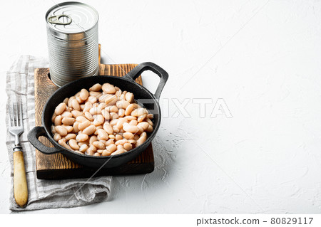 Canned white beans, with metal can, in cast iron frying pan, on white stone surface, with copy space for text Canned white beans, with metal can, in cast iron frying pan, on white stone surface, with copy space for text 80829117