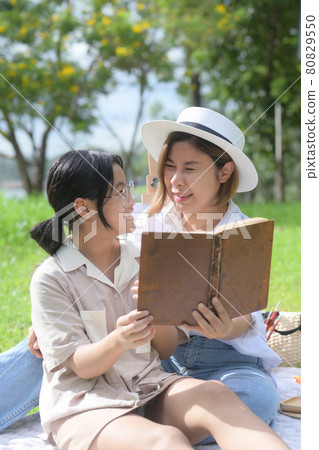 Young mother and daughter reading a book in the park. 80829550