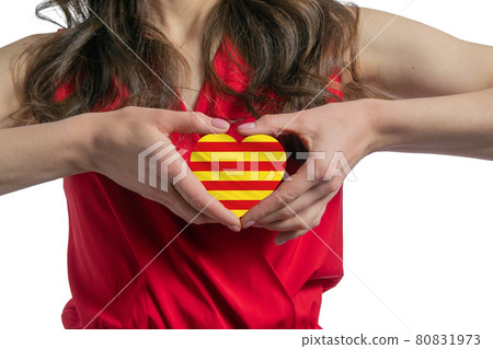Love Catalonia. The woman holds a heart in the form of the flag of Catalonia on her chest. Concept of patriotism Love Catalonia. The woman holds a heart in the form of the flag of Catalonia on her chest. Concept of patriotism 80831973