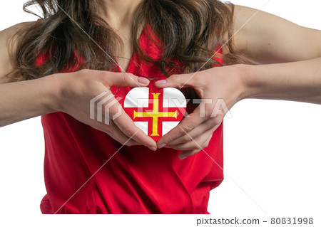 Love Guernsey. The woman holds a heart in the form of the flag of Guernsey on her chest. Concept of patriotism 80831998