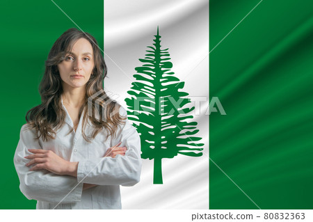 Medicine in Norfolk Island. Happy beautiful female doctor in medical coat standing with crossed arms against the background of the flag of Norfolk Island 80832363