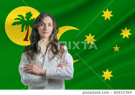 Medicine in Cocos Islands. Happy beautiful female doctor in medical coat standing with crossed arms against the background of the flag of Cocos Islands 80832364