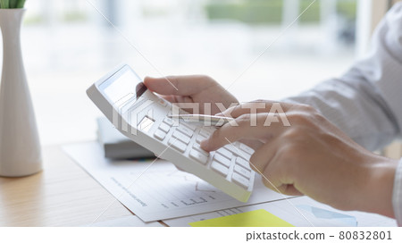 Young Asian businessman presses a calculator to calculate income tax and corporate income in a private office, Finance, Accounting, Tex, Statistical graphs of marketers investing in real estate. Young Asian businessman presses a calculator to calculate income tax and corporate income in a private office, Finance, Accounting, Tex, Statistical graphs of marketers investing in real estate. 80832801