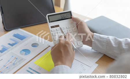 Young Asian businessman presses a calculator to calculate income tax and corporate income in a private office, Finance, Accounting, Tex, Statistical graphs of marketers investing in real estate. Young Asian businessman presses a calculator to calculate income tax and corporate income in a private office, Finance, Accounting, Tex, Statistical graphs of marketers investing in real estate. 80832802