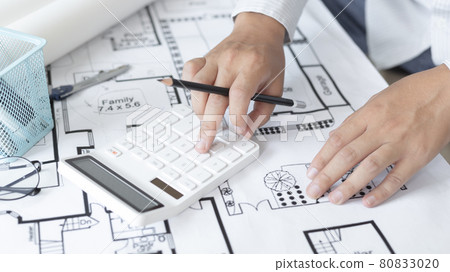 Male engineer or architect is pressing a calculator to calculate the building's structure and balance, Architects or engineers are designing buildings using calculator to calculate the physical struct Male engineer or architect is pressing a calculator to calculate the building's structure and balance, Architects or engineers are designing buildings using calculator to calculate the physical struct 80833020