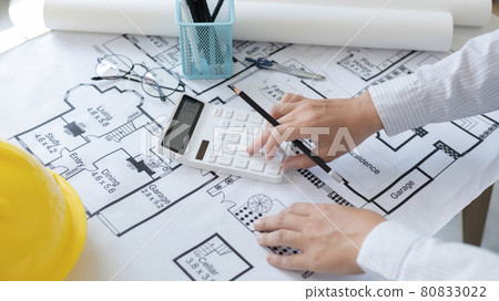 Male engineer or architect is pressing a calculator to calculate the building's structure and balance, Architects or engineers are designing buildings using calculator to calculate the physical struct Male engineer or architect is pressing a calculator to calculate the building's structure and balance, Architects or engineers are designing buildings using calculator to calculate the physical struct 80833022