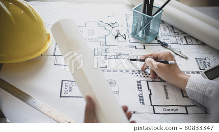Architectural building design and construction plans with blueprints, Young man was designing a building or architecture with a pen ruler, pencil, tape measure, architect hat and other equipment. 80833347