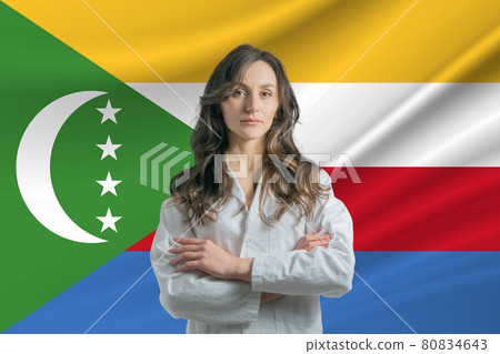 Medicine in Comoros Happy beautiful female doctor in medical coat standing with crossed arms against the background of the flag of Comoros 80834643