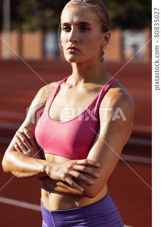 Close-up portrait of professional female athlete, runner and beautiful woman training at public stadium, sport court or running track outdoors. Looks concentrated, motivated 80835027