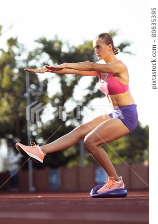 One Caucasian woman, female athlete, runner practicing alone at public stadium, sport court or running track outdoors. Summer sport games. One Caucasian woman, female athlete, runner practicing alone at public stadium, sport court or running track outdoors. Summer sport games. 80835395