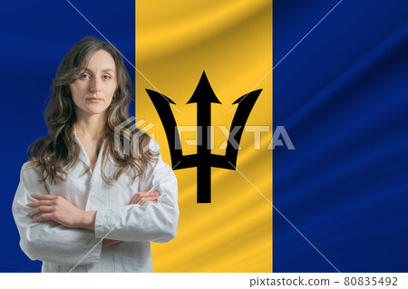 Medicine in Barbados. Happy beautiful female doctor in medical coat standing with crossed arms against the background of the flag of Barbados 80835492
