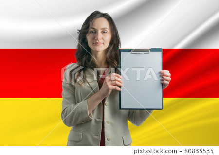 Study in South Ossetia. Beautiful woman holding a sheet of paper in her hands. Girl on the background of the flag of South Ossetia Study in South Ossetia. Beautiful woman holding a sheet of paper in her hands. Girl on the background of the flag of South Ossetia 80835535