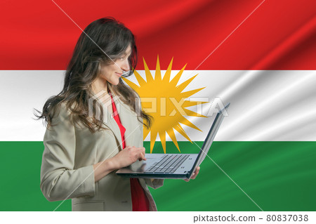Freelance in Kurdistan. Beautiful young woman freelancer uses laptop computer against the background of the flag of Kurdistan 80837038