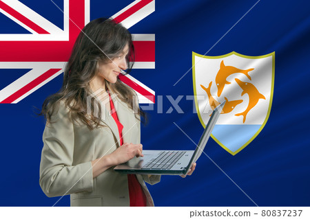 Freelance in Anguilla. Beautiful young woman freelancer uses laptop computer against the background of the flag of Anguilla Freelance in Anguilla. Beautiful young woman freelancer uses laptop computer against the background of the flag of Anguilla 80837237