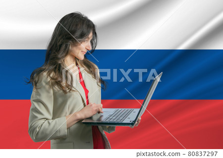 Freelance in Russia. Beautiful young woman freelancer uses laptop computer against the background of the flag of Russia 80837297
