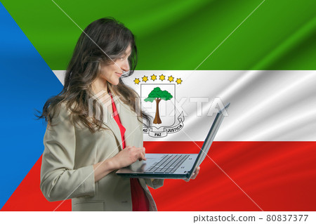 Freelance in Equatorial Guinea Beautiful young woman freelancer uses laptop computer against the background of the flag of Equatorial Guinea Freelance in Equatorial Guinea Beautiful young woman freelancer uses laptop computer against the background of the flag of Equatorial Guinea 80837377