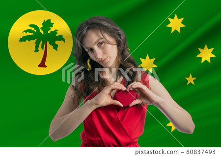 Love Cocos Islands. A girl holds a heart on her chest in her hands against the background of the flag of Cocos Islands. The concept of patriotism Love Cocos Islands. A girl holds a heart on her chest in her hands against the background of the flag of Cocos Islands. The concept of patriotism 80837493